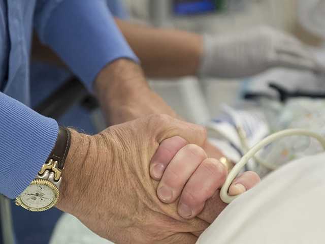 Close up of two adult hands gently holding a child's hand