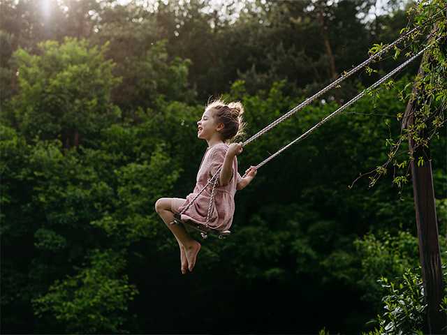 Little girl smiling with on a swing set at the park.