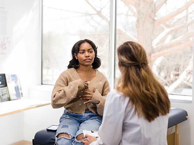 Teenage girl talking to a medical professional about her feelings and symptoms.