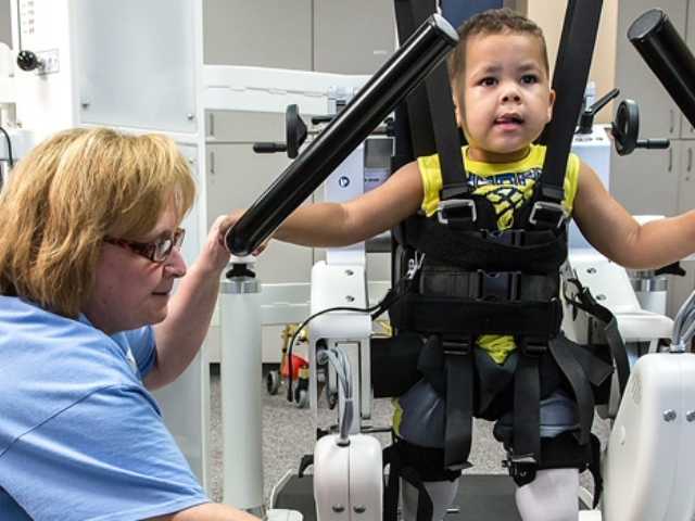 Little boy working through exercises at rehab facility with a medical professional.