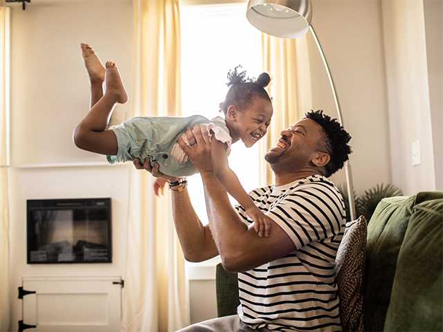 Father and his young daughter playing at home while laughing and smiling.