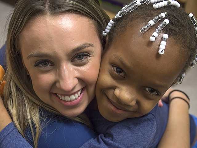 Smiling young Black girl hugs doctor in the pediatric fracture clinic