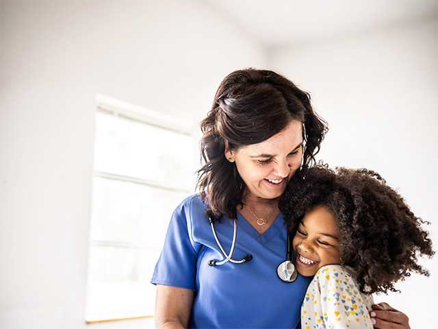 medical professional and young female patient hug and smile after a checkup