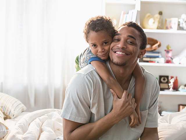 Father and his young child at home smiling.