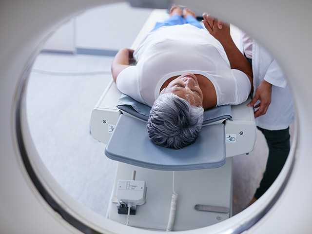 Woman with short grey hair comfortably lies down for a CT scan at a Corewell Health imaging facility