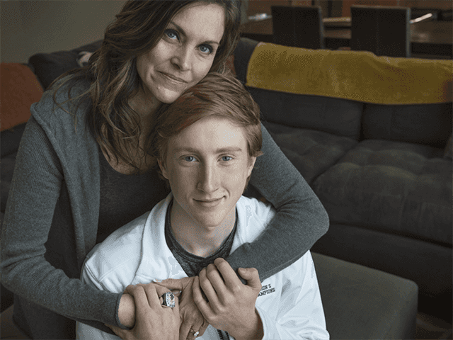 Mother hugs her teenage son from behind as they smile