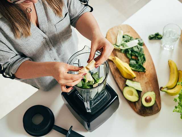 Woman's hands putting fruit in a blender to make a smoothie