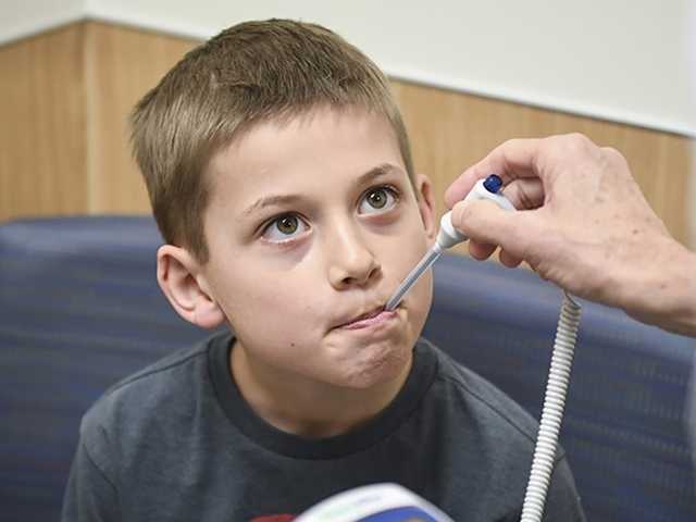 Preteen boy getting temperature taken with thermometer in his mouth.