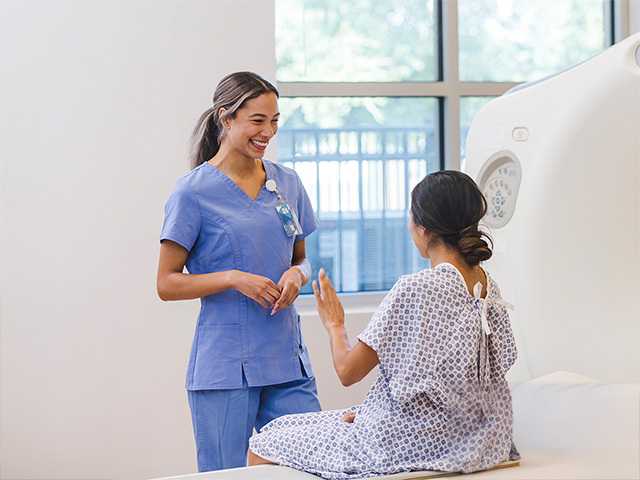 Smiling Corewell Health imaging specialist speaks with a patient before she has an MRI scan