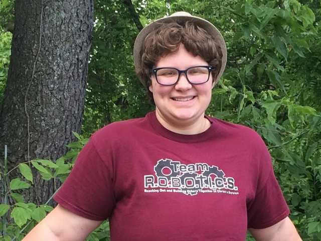 Smiling teenage girl in a red shirt standing outdoors