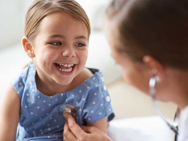 Smiling young girl in a blue shirt with a stethoscope on her chest