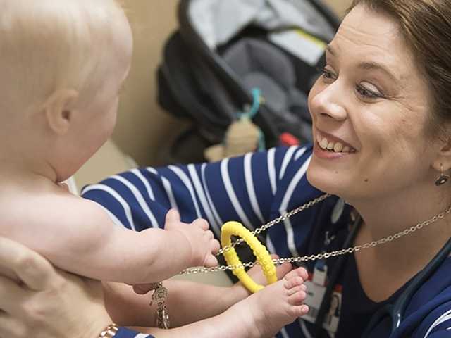 Smiling doctor reaches out to baby boy in the movement disorders clinic