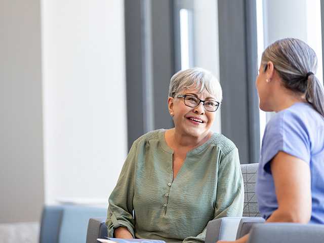Smiling elderly woman speaks with a Corewell Health heart and vascular specialist in an exam room