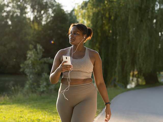 woman wearing light blue jacket running next to water