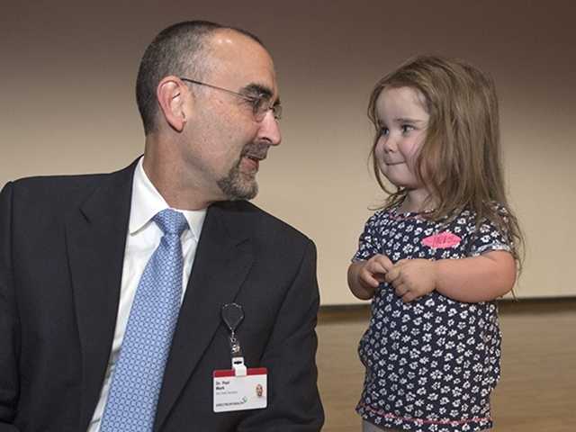 Doctor sits down next to young girl patient and speaks with her