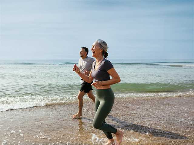 Man and woman running side-by-side on beach