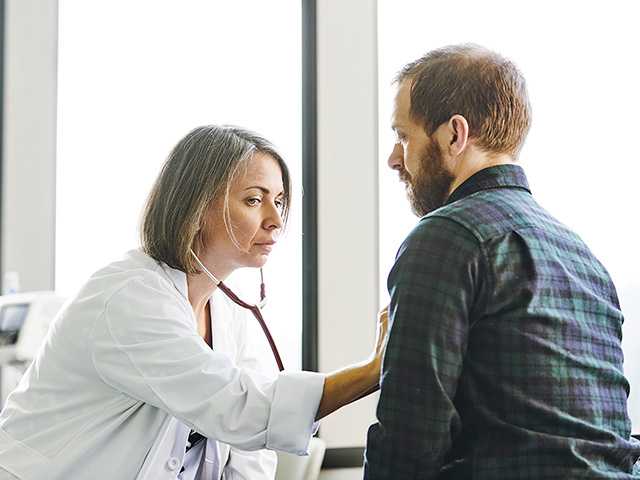 fillerFemale doctor in white lab coat uses a stethoscope to listen to a man's heartbeat