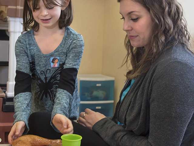 Woman and young girl playing with pretend food and dishes.