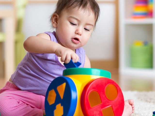 Little girl developing skills by playing with blocks and toys.