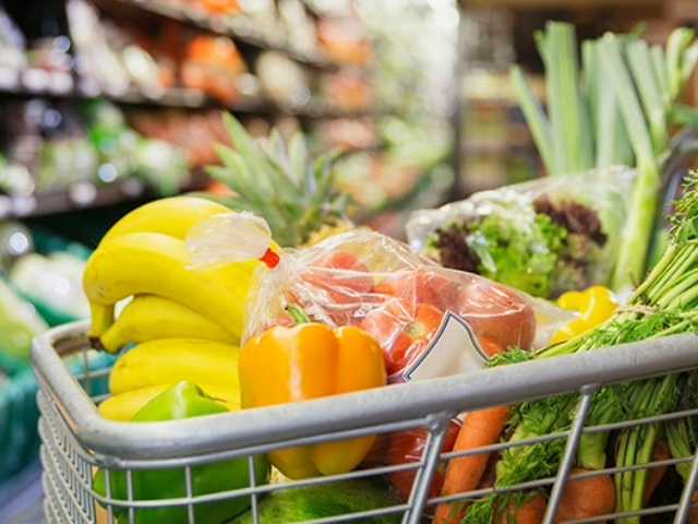 Grocery cart filled with produce in a grocery store