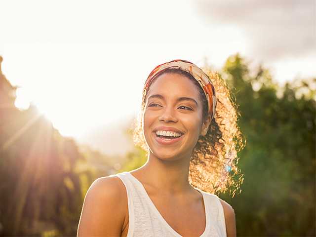 Smiling Black woman standing outside in the sunset