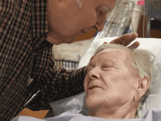 Gentleman leaning down to kiss woman on the forehead