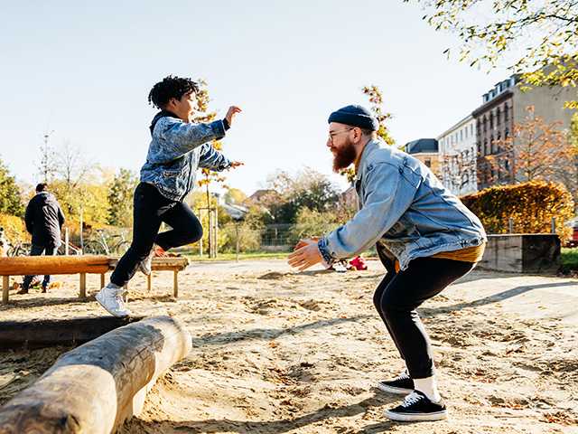 Little boy jumping of a tree log and into his fathers arms.