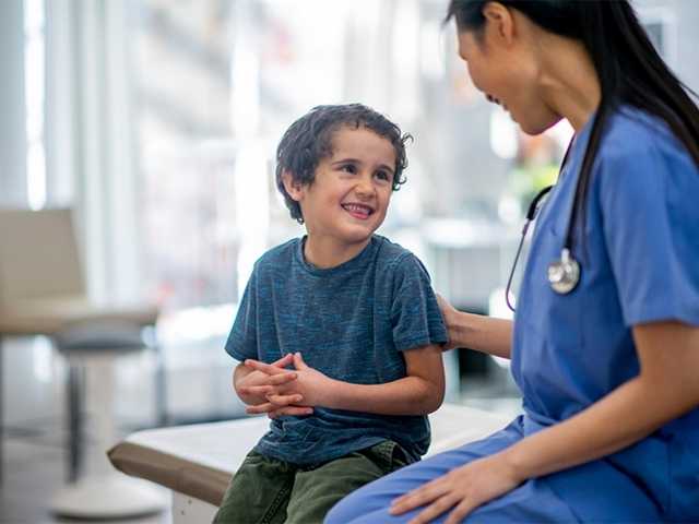 Health care provider talking with young boy.