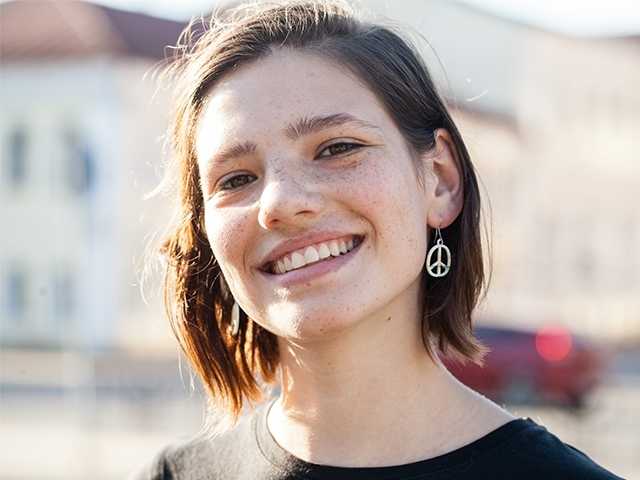 Smiling teenage girl with freckles and brown hair in the sunshine