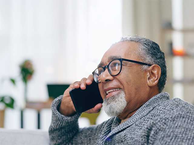 old male speaking on the phone to someone while smiling