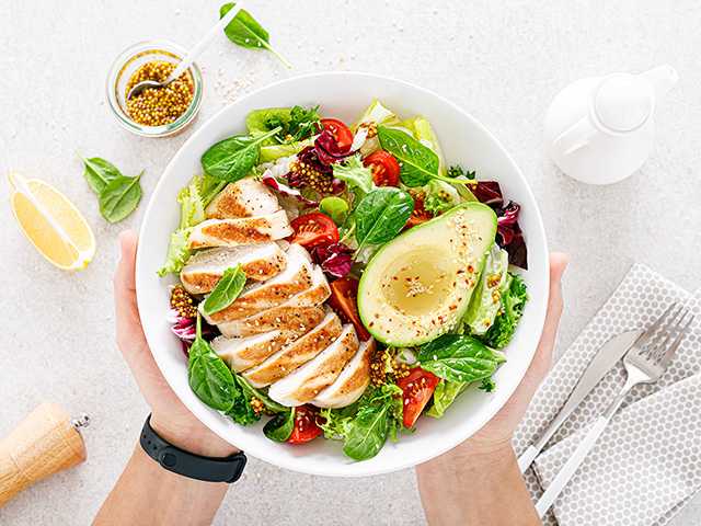 Customer holding a salad while eating in the cafeteria
