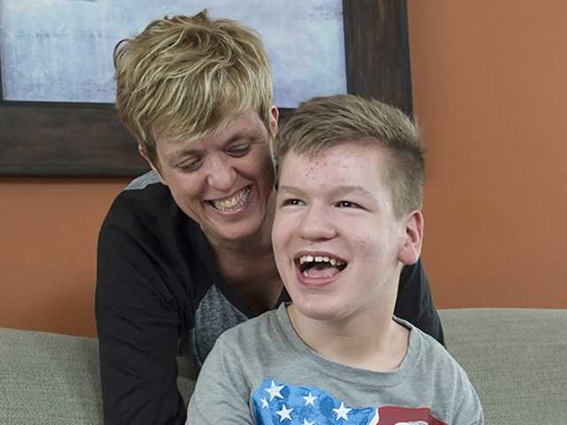 Smiling preteen boy sits near his mother in the pediatric orthopedics clinic