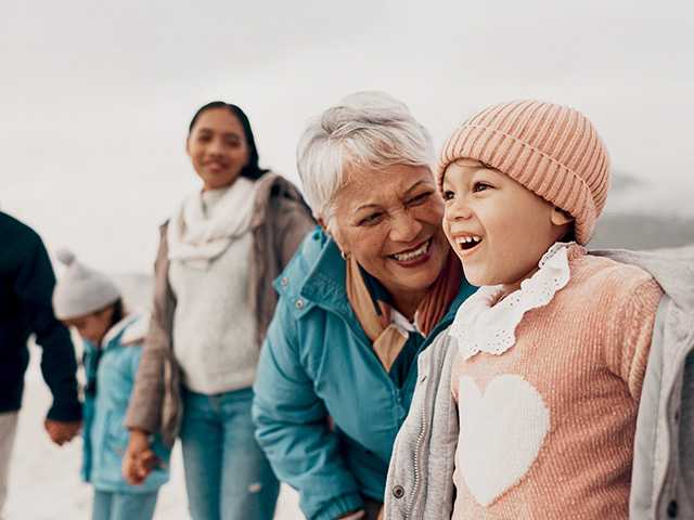 Smiling elderly white woman kneels down next to her granddaughter