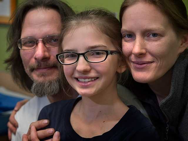 Smiling preteen girl with her smiling mother and father in the pediatric orthopedics clinic