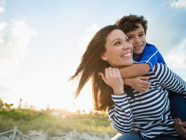 Smiling boy and his mother play outdoors