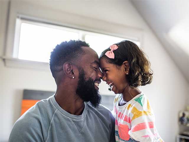 Father and young daughter smiling at each other.