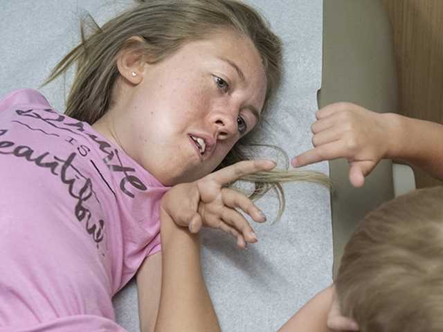 Teenage girl lies on exam bed in the biochemical genetics clinic