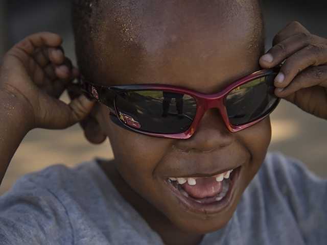 Smiling young Black boy wearing red sunglasses