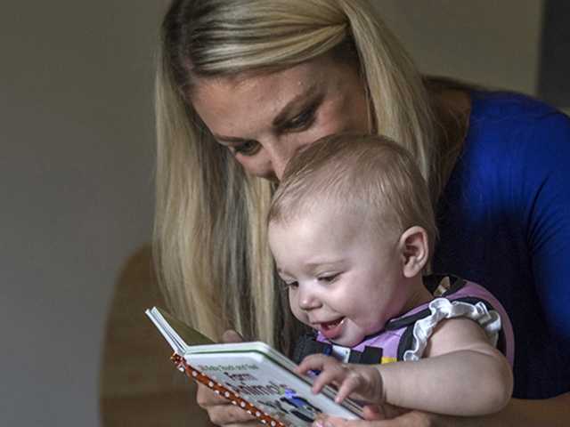 Mother reads a book to her smiling toddler