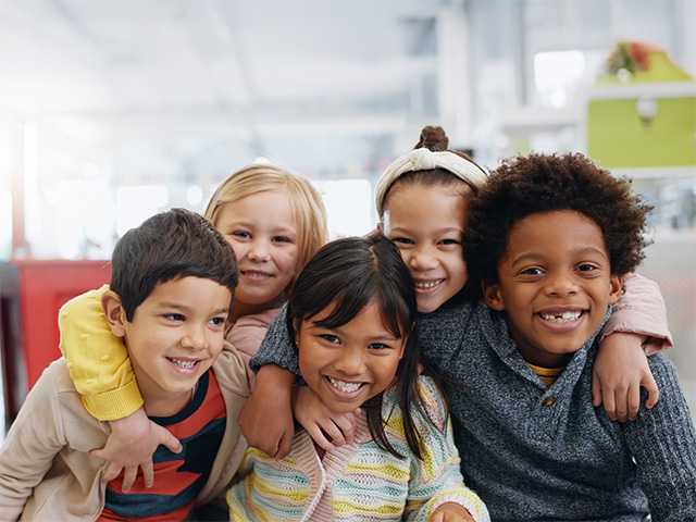 A group of children hugging and smiling at school.