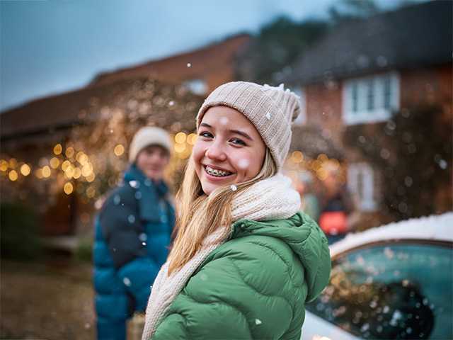 Teen girl smiling for the camera while other teens are in the background.