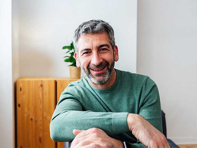 A man sitting in a chair, smiling warmly.