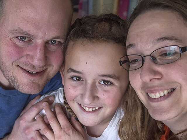 Smiling teenage girl is hugged by her mother and father