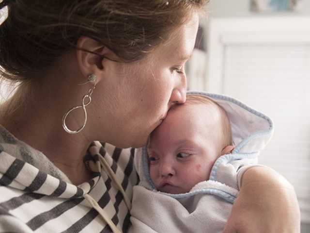 Mother holds a young baby wrapped in a blanket