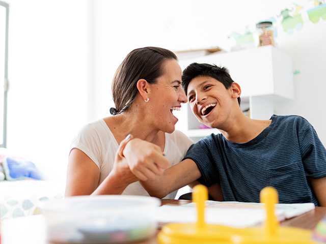 Preteen boy and his mother smiling and interacting at the table.
