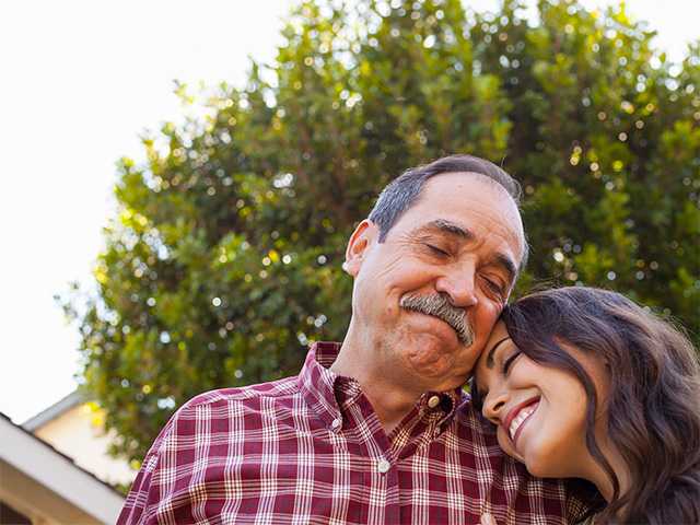 Older man with grey hair hugs his adult daughter