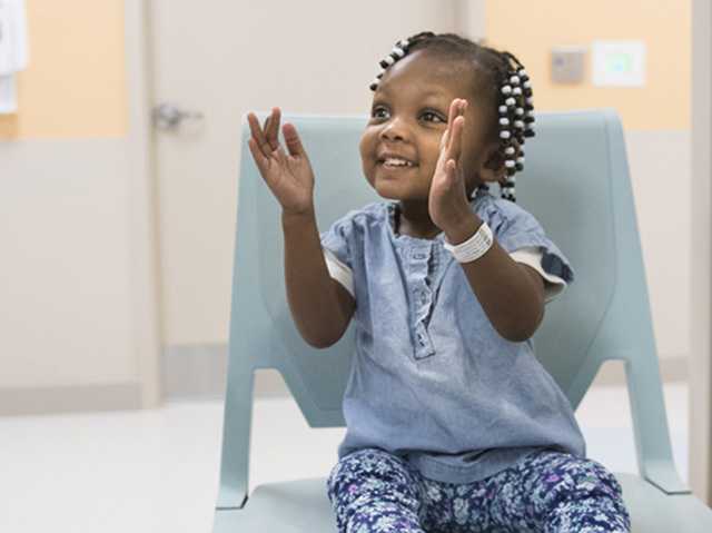 Young Black girl sitting in a chair clapping her hands