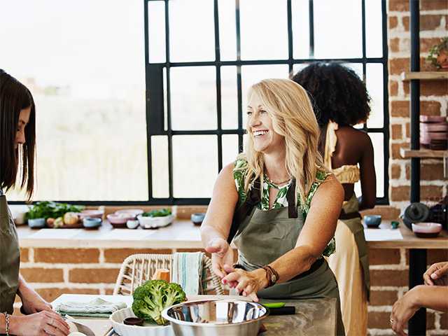 Smiling woman wearing a green apron while participating in a culinary medicine cooking class